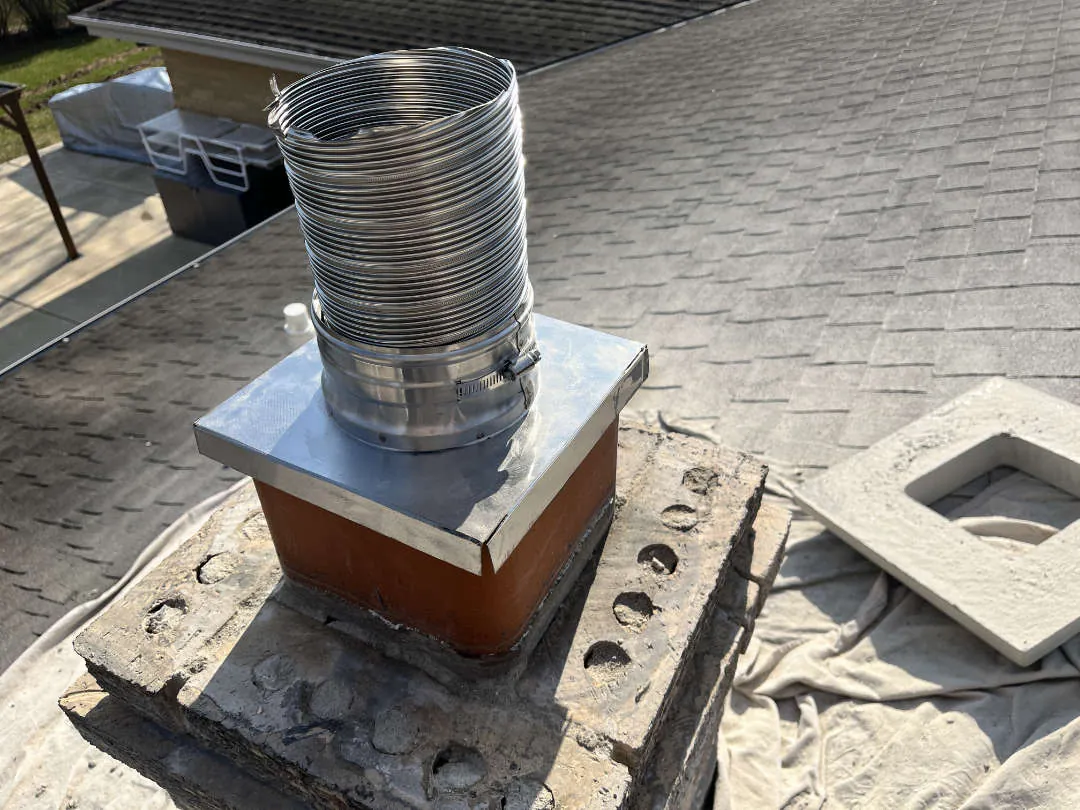 Stainless liner top plate set over a clay flue tile during a chimney relining