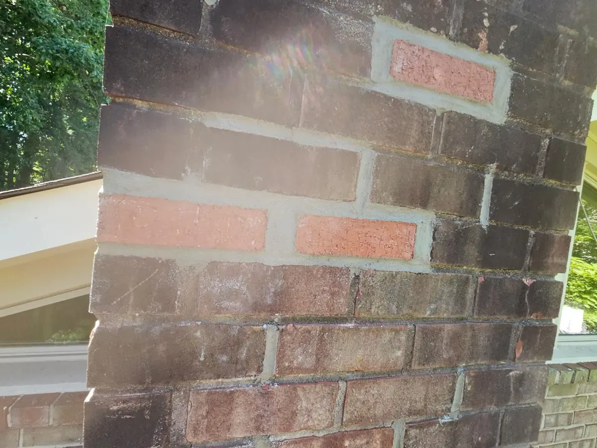 Replacement bricks set in fresh mortar joints on an older brick chimney