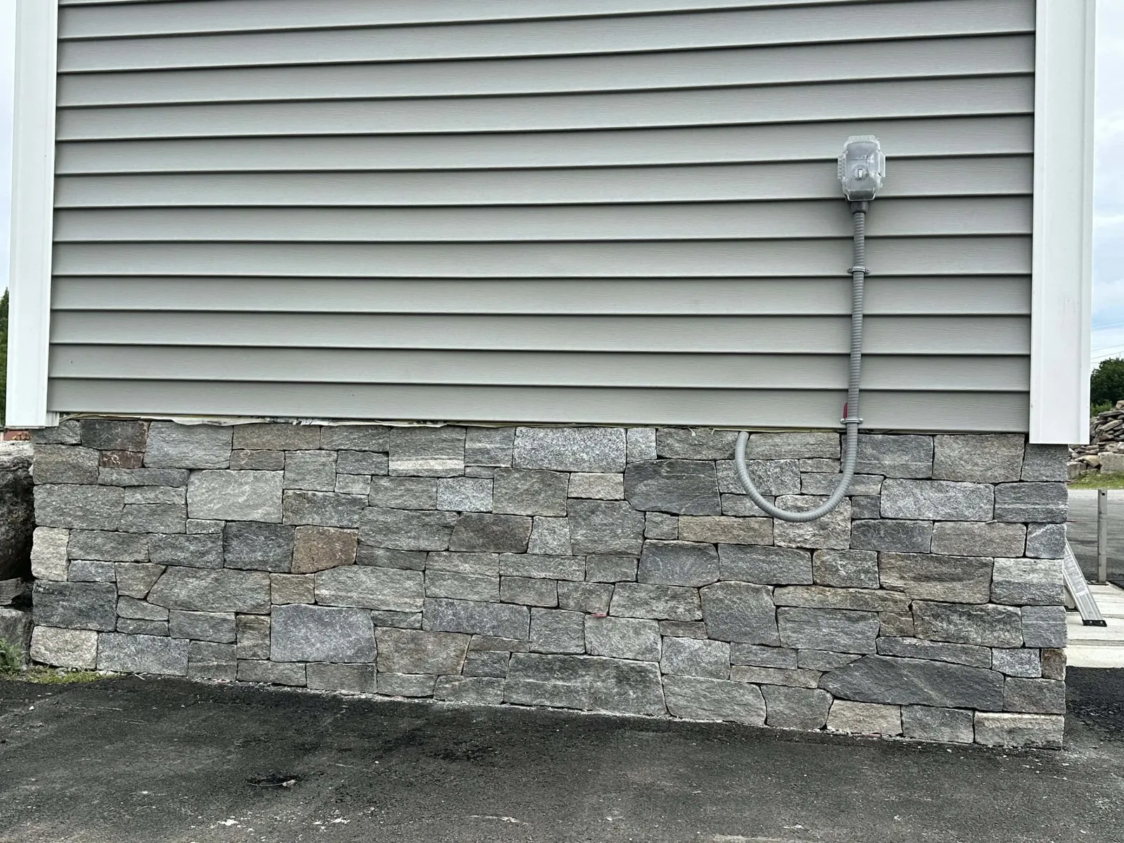 Natural thin stone veneer set along the lower wall of a sided house